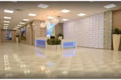 Spacious modern reception lobby with polished tile floor, illuminated front desk, decorative wall panels and planters.