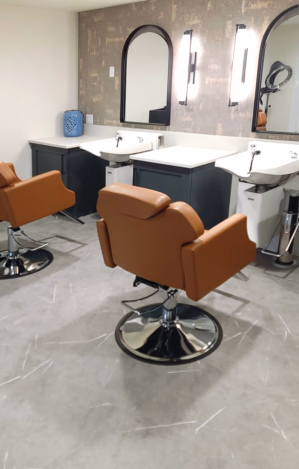 Salon area with brown styling chairs facing shampoo sinks and mirrors in a clean interior space.