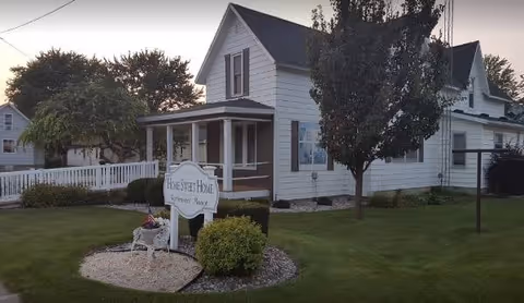 White retirement home exterior with a small front porch and manicured lawn