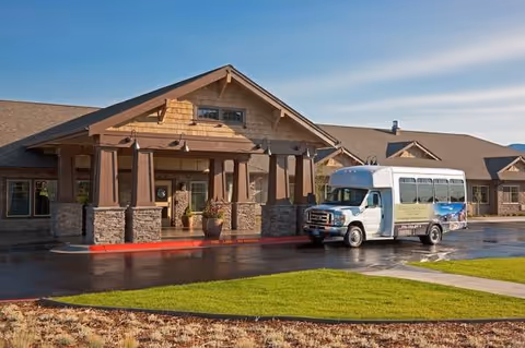 Exterior view of Spring Creek Inn Memory Care Community with a shuttle bus at the entrance.