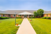 Brick, single-story healthcare facility with central entrance, walkway, and manicured lawn.