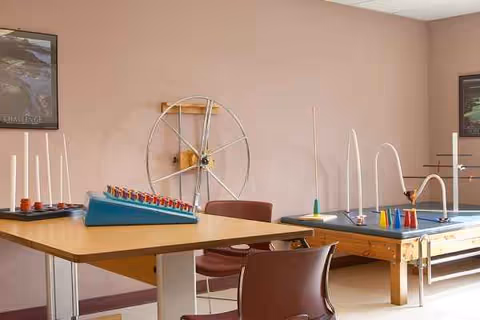 Interior recreation/therapy room in a senior facility with exercise equipment and tables.