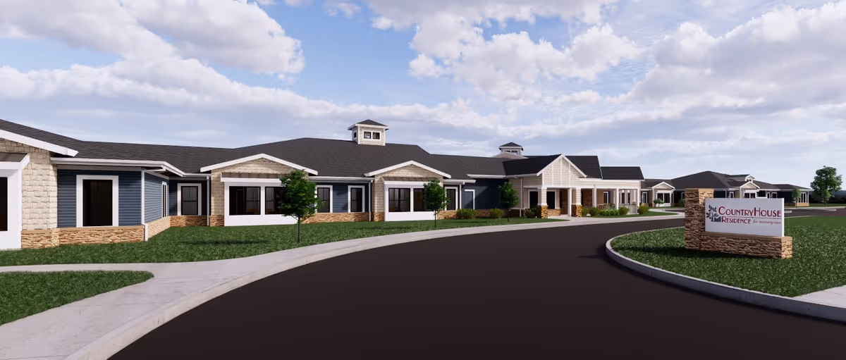 Exterior view of CountryHouse Residence, a single-story senior living facility with a curved driveway, green lawn, and a sign displaying the facility's name at the entrance.