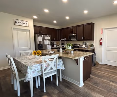 Open-concept kitchen and dining area with dark wood cabinets, island, and floral tablecloth.
