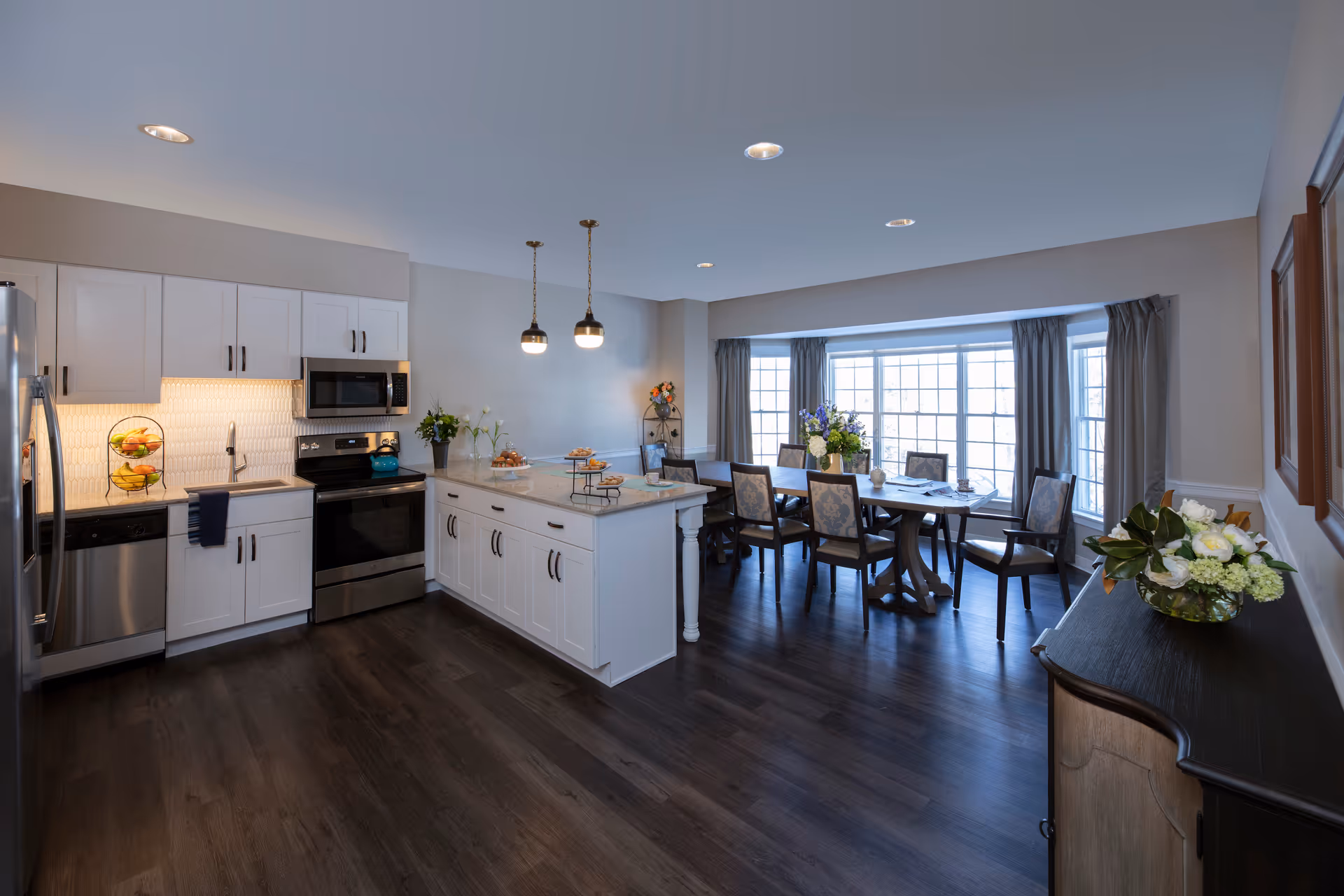 Bright open-concept kitchen with a central island and an adjoining dining area by large bay windows.