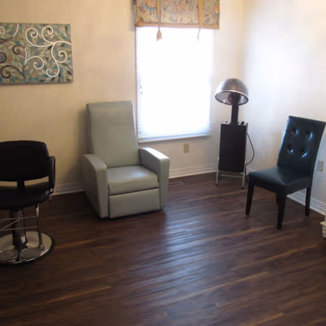 Small interior room with three chairs, a window, wall art and a standing hooded hair dryer.