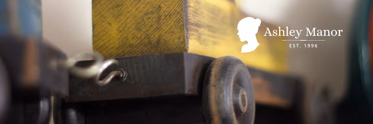 Close-up image of a vintage wooden toy cart with a yellow box on top, featuring a small black wheel in focus.