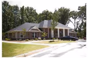 Front view of a single-story senior living facility with a driveway and parked car.