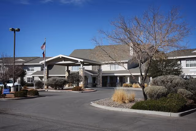 SunRidge At Cambria exterior building entrance with driveway, flagpole, and landscaping.