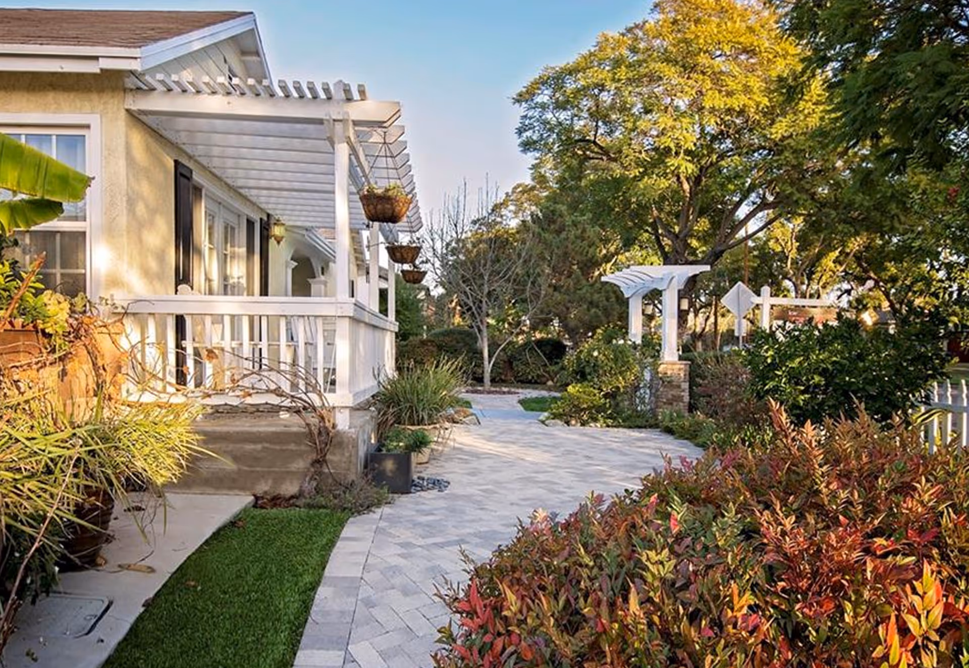Front porch and landscaped walkway of a house with a pergola and garden.