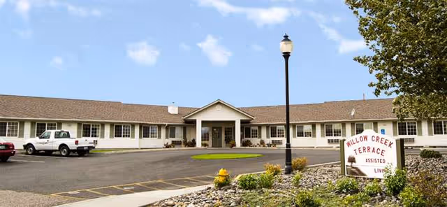 Front view of Willow Creek Terrace, a single-story senior living facility with parking and landscaped entrance.
