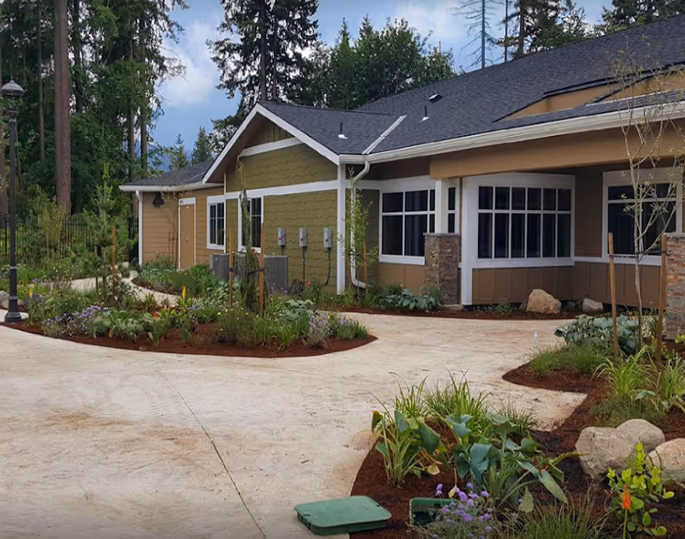 Exterior view of a Ciel of Issaquah senior living building with garden landscaping and walkway