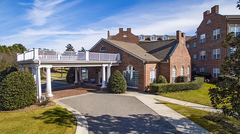 Brick senior living facility The Carolina Inn with covered entrance and landscaped grounds.