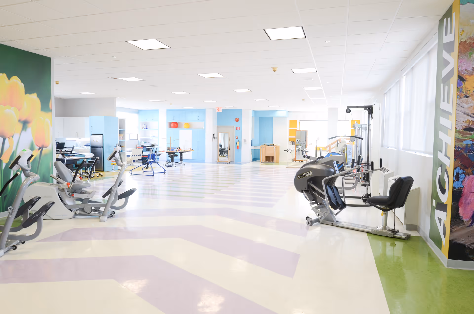 Bright, spacious therapy and exercise room with cardio machines and rehabilitation equipment in a senior facility.