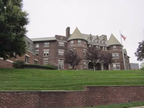 Job Haines Home exterior: brick building with turrets, flag, and green lawn.
