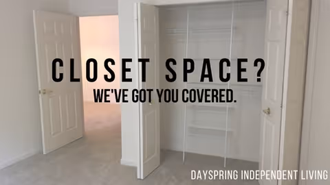 An empty closet with white bi-fold doors open, showing hanging rods and shelves inside. The closet is in a room with light-colored carpet and walls. Text overlay reads 'CLOSET SPACE? WE'VE GOT YOU COVERED.' and 'DAYSPRING INDEPENDENT LIVING'.