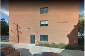 Exterior of Tucker House Rehabilitation & Nursing Center building with two parked cars nearby.