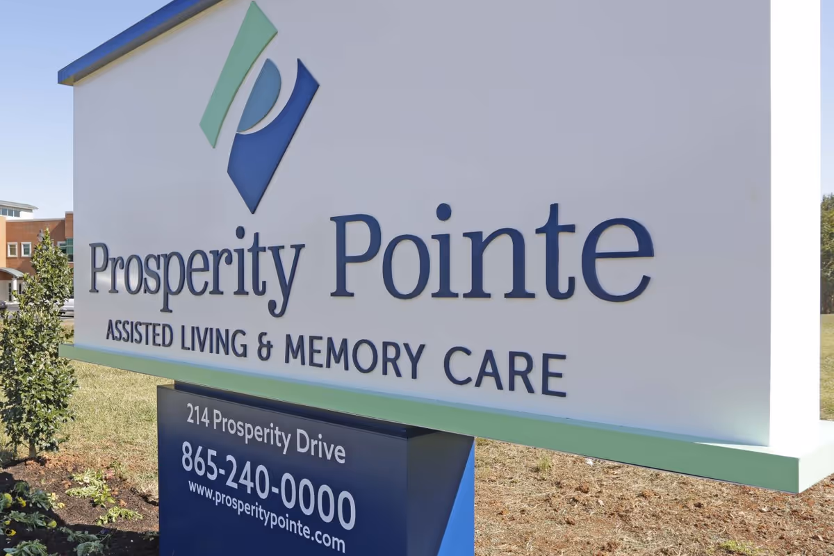 Outdoor entrance sign for 'Prosperity Pointe Assisted Living & Memory Care' showing the facility name, address and phone number.