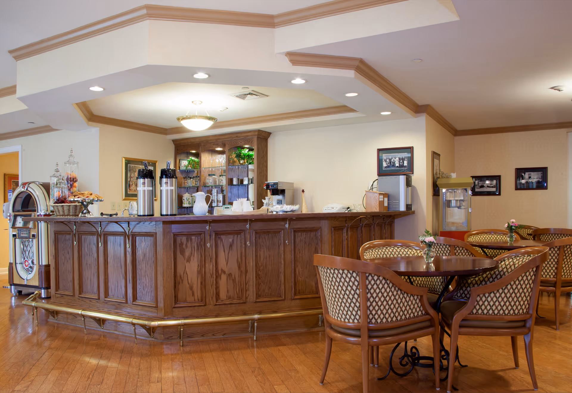 Wood-paneled coffee bar with urns and a jukebox and several round tables with upholstered chairs in a dining/lounge area.