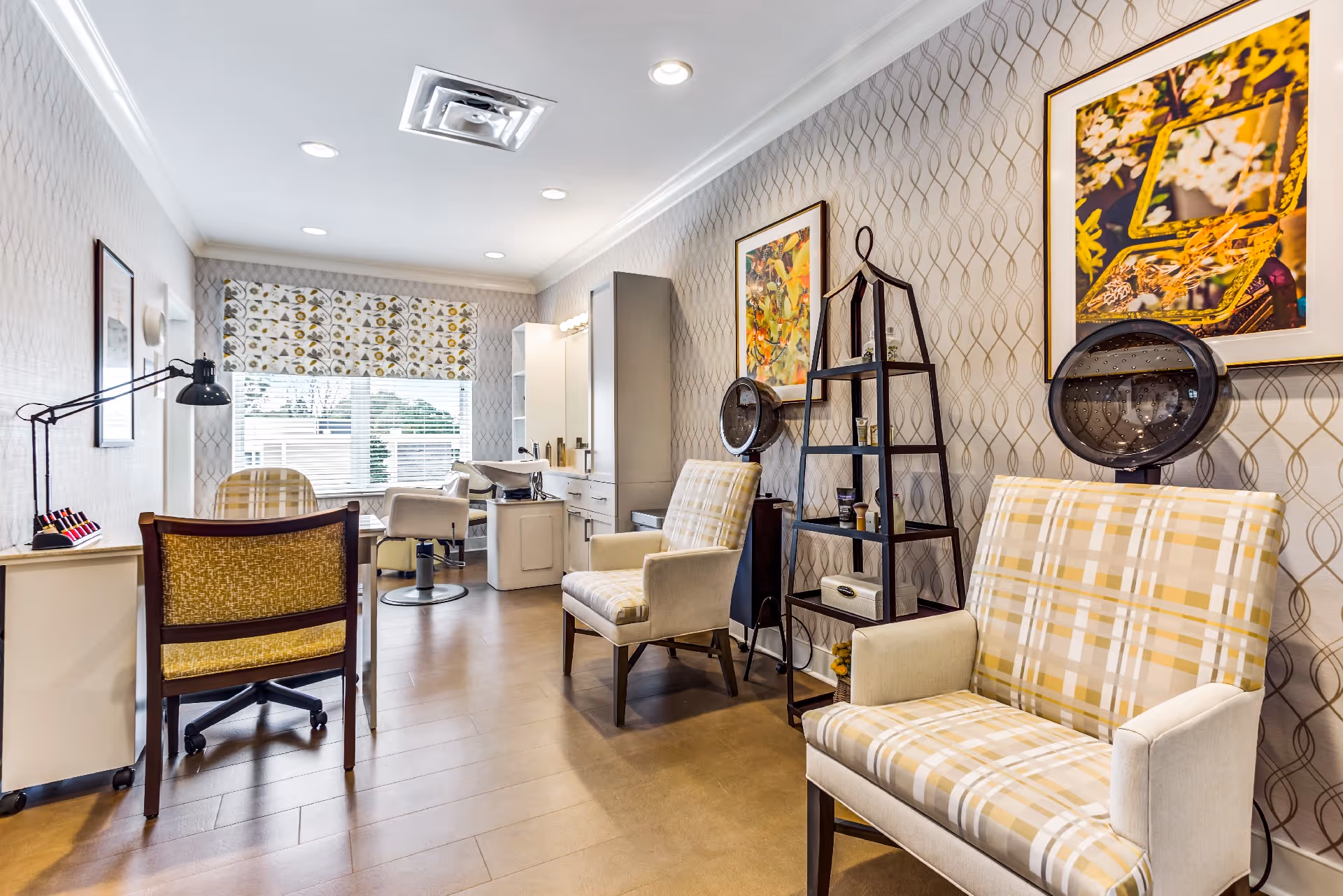 Well-lit salon area with plaid armchairs, styling stations, and shelving in a senior living community.