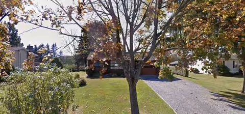 Pond View Manor exterior: gravel driveway, green lawn, and trees in front.