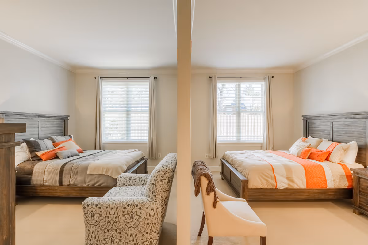 Two adjacent, symmetrically furnished bedrooms separated by a partial wall, each with a bed, window, and seating.