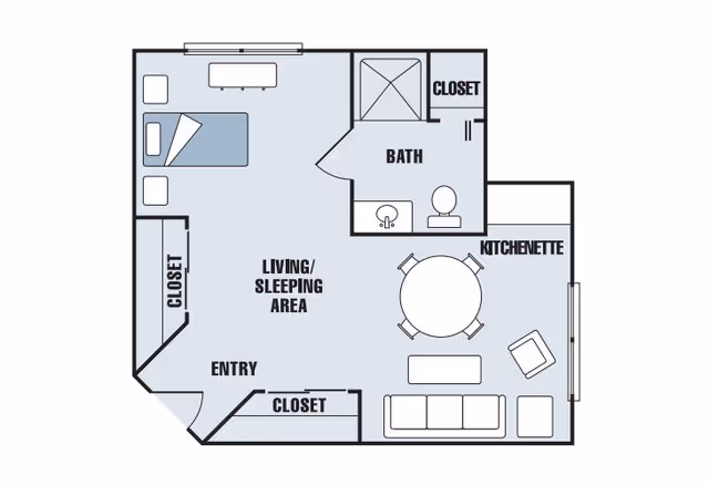 Floor plan of a senior living studio apartment at Carriage House Senior Living Community showing a living/sleeping area with a bed, sofa, chair, and table, a kitchenette with a round dining table and four chairs, a bathroom with a shower, sink, and toilet, and three closets near the entry and bath.