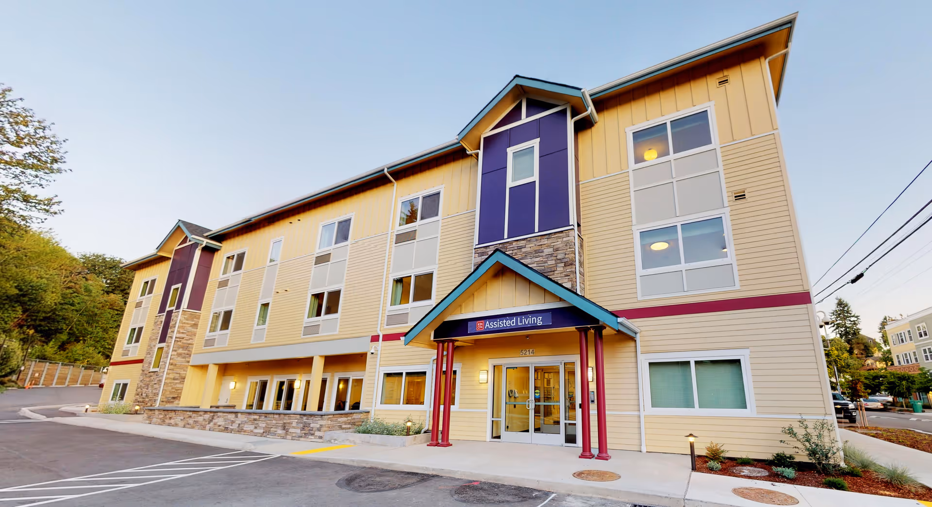 Front exterior of a three-story assisted living building with a covered entrance and multiple windows.