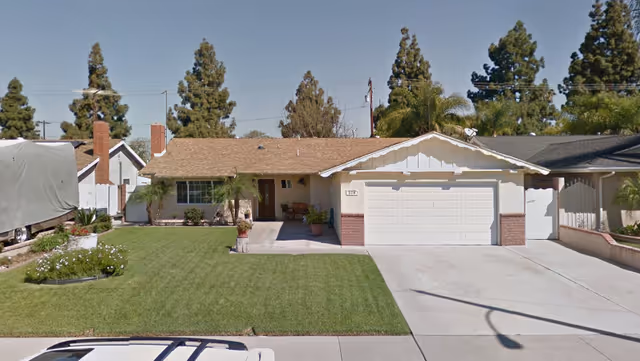 Front view of a single-story house with a manicured lawn and attached garage.