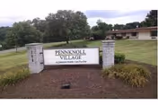 Pennknoll Village entrance sign between stone columns with landscaping.
