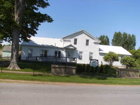White, single-story facility with a sign reading East Road Adult Home, front lawn, and street view.