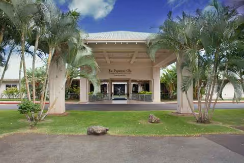Front entrance of Ka Punawai Ola senior living, with palm trees and a covered portico.