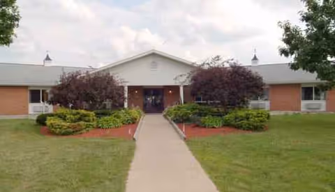 Front entrance of Miller's Merry Manor senior living facility with a walkway and shrubs.