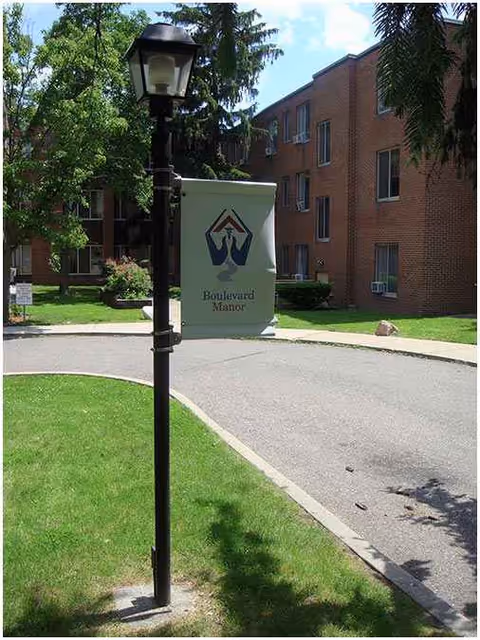 Boulevard Manor sign along a curved driveway in front of a brick building.