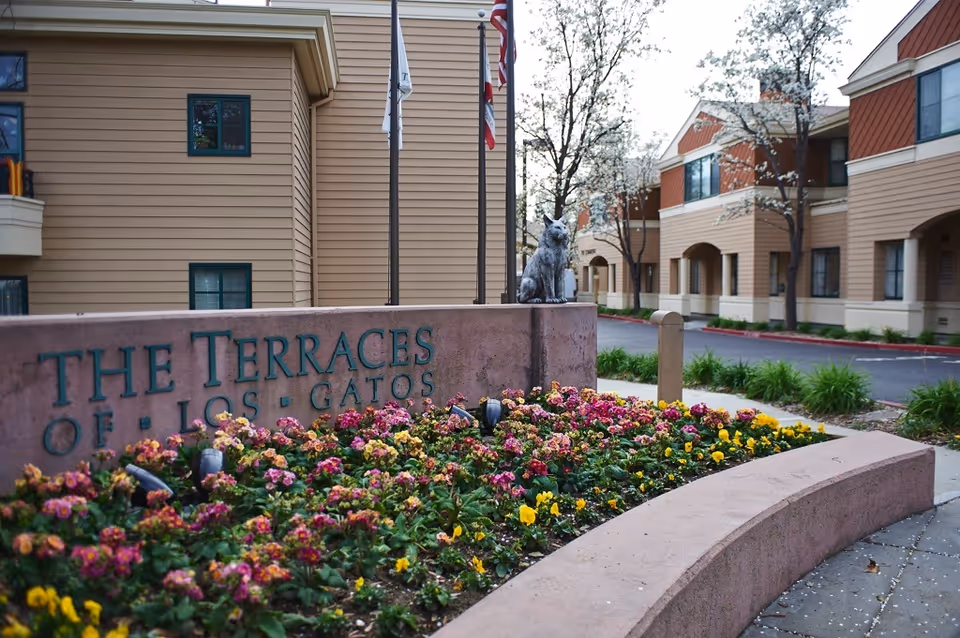 Entrance sign and landscaped flower bed in front of The Terraces of Los Gatos senior living buildings.
