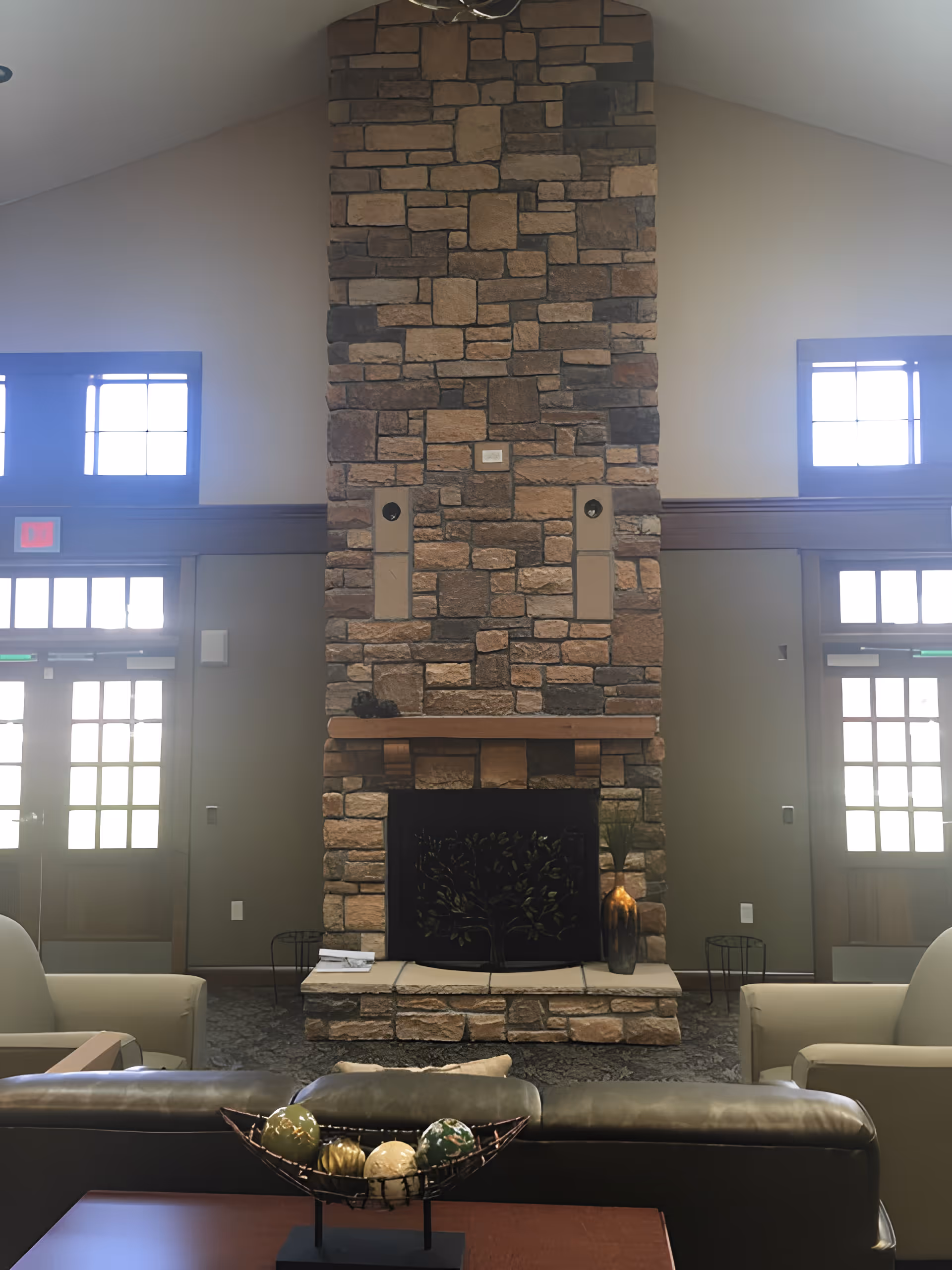 A tall stone fireplace in a spacious common living room with seating and decorative accents.