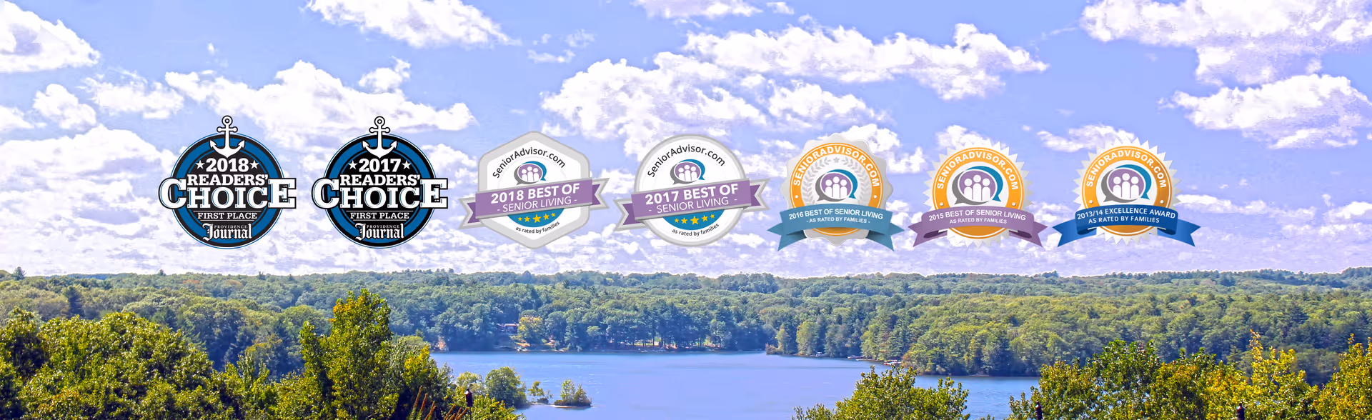 Scenic view of a lake surrounded by dense green trees under a partly cloudy blue sky, with multiple award badges displayed across the sky area.