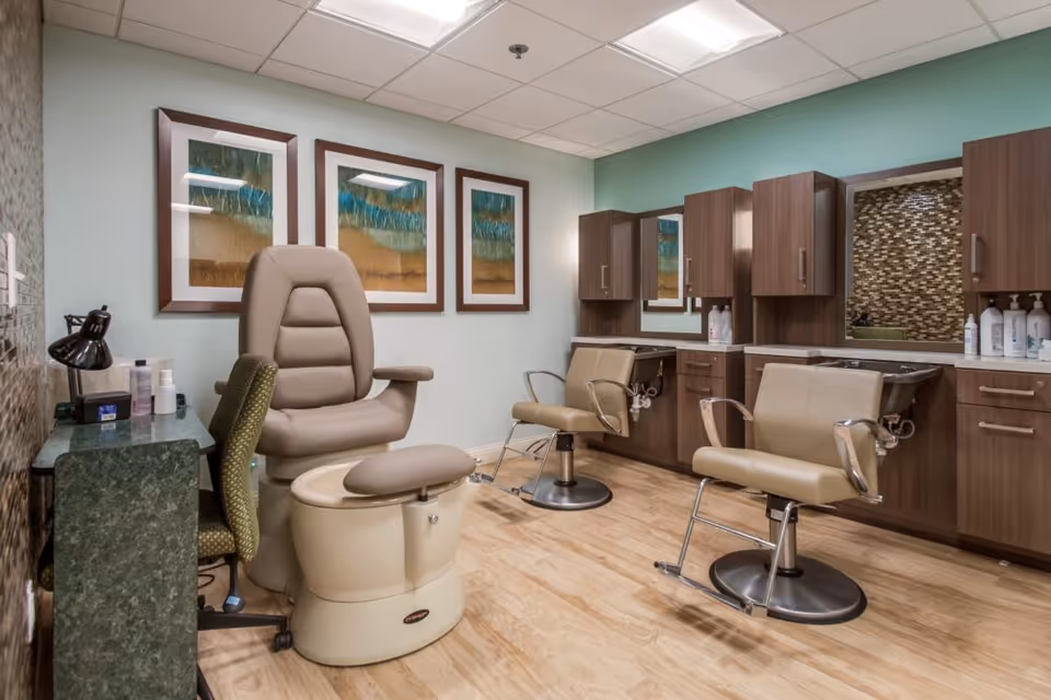 A salon-style interior with a pedicure chair, styling chairs, washbasins and wood cabinetry beneath framed artwork.
