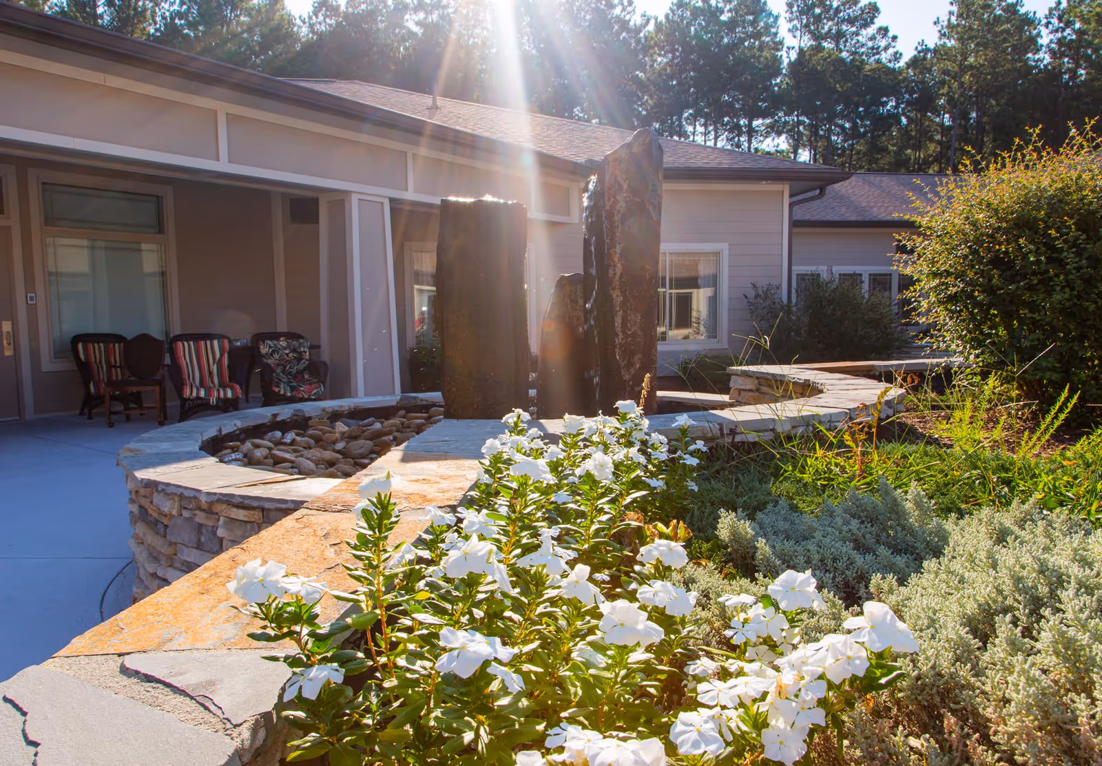 Stone fountain and white flowers in a landscaped courtyard outside the assisted living building.