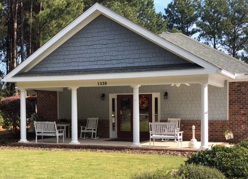 Front view of a Sunrise at Parkway building with a covered porch, white columns, and benches.