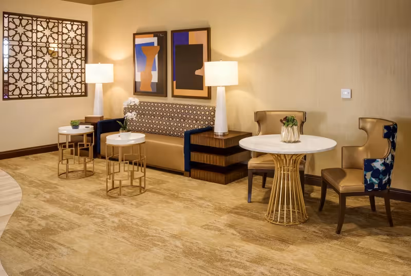 Stylish lounge area with a sofa, chairs, round tables, lamps, and framed wall art.
