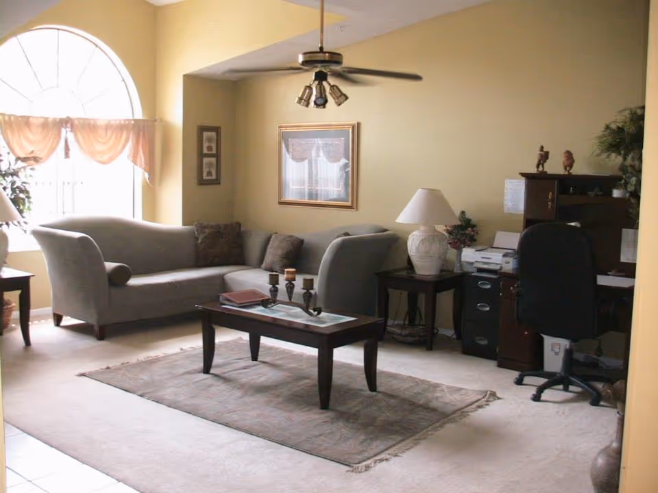 Cozy living room in Sunshine Assisted Living with sofa, coffee table, rug, and a desk area.