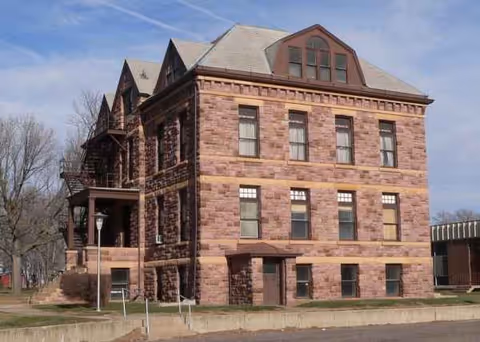 Brick four-story geriatric services building with arched windows and a small surrounding lot.
