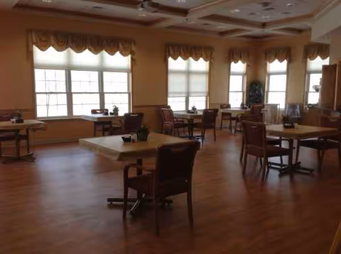 Spacious Kingston of Ashland dining room with tables, chairs, and large windows along walls.
