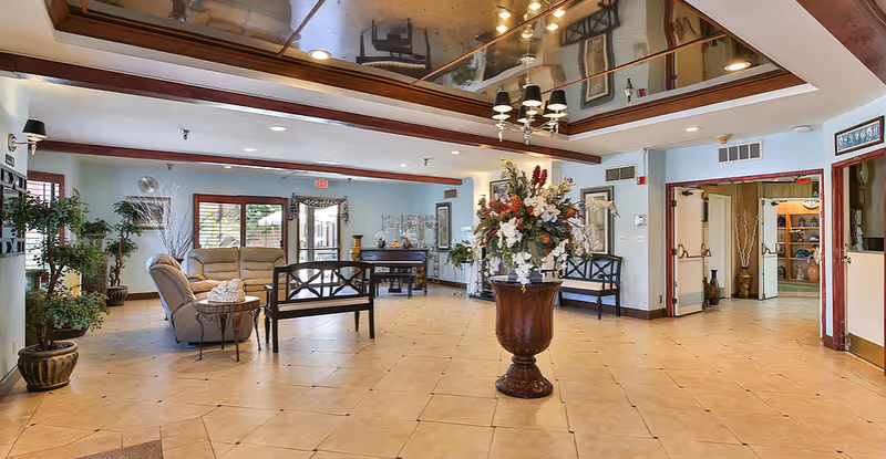 Spacious lobby seating area with plants, a central floral arrangement, and decorative ceiling mirrors.