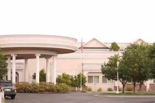 Exterior view of Heirloom Inn with circular entrance canopy, columns, and parking lot.