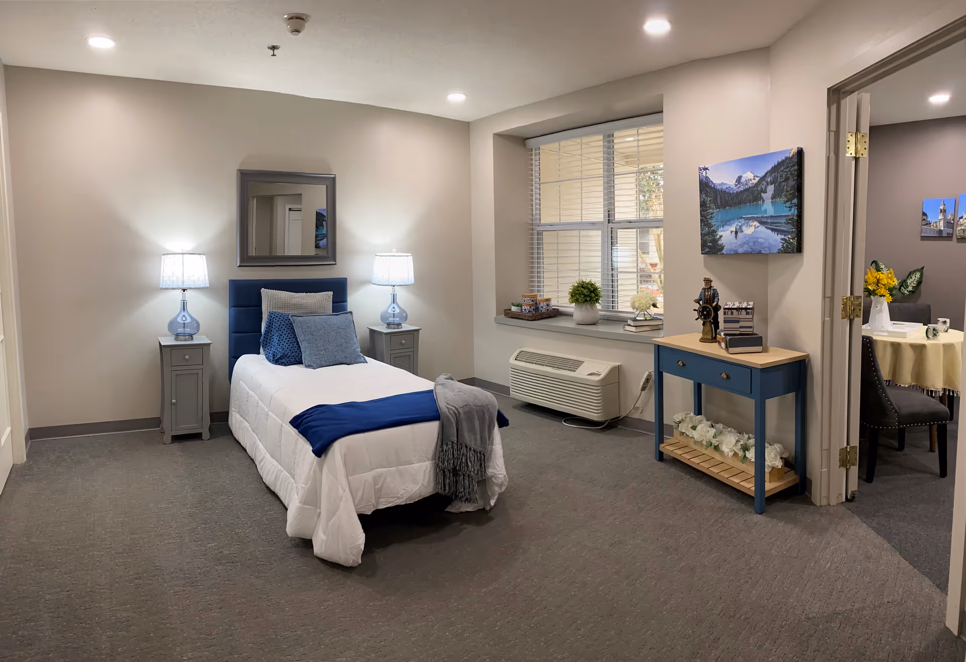 Furnished bedroom in a senior living facility with a bed, nightstands, and a window.