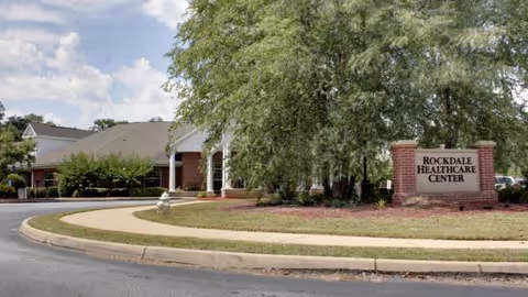Exterior view of Rockdale Healthcare Center entrance with lawn and brick sign.