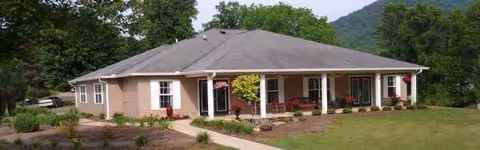 A single-story senior care home with a front porch and landscaping.