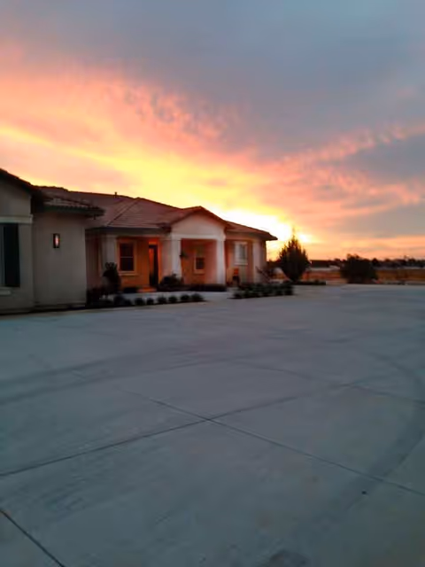 Exterior view of Bird of Paradise Manor with a wide concrete front and sunset sky.